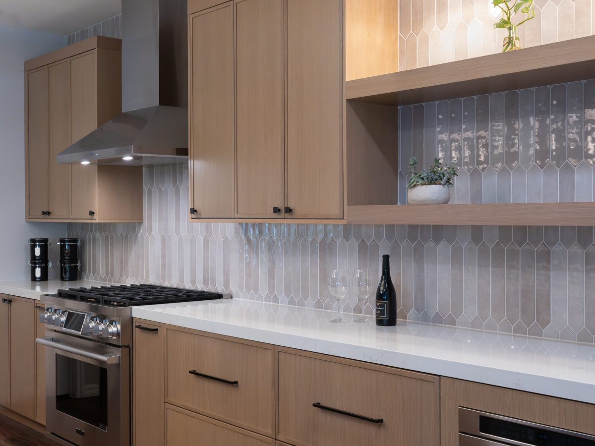 Modern kitchen with warm stained oak cabinetry, dark bronze hardware, and handmade-look picket backsplash tile, Reveal Interior Design Las Vegas