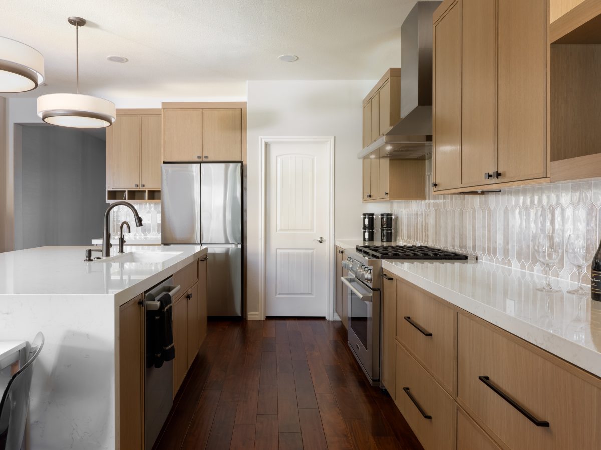 Warm oak shaker kitchen with quartz countertops and picket-shaped backsplash tile, Reveal Interior Design Las Vegas