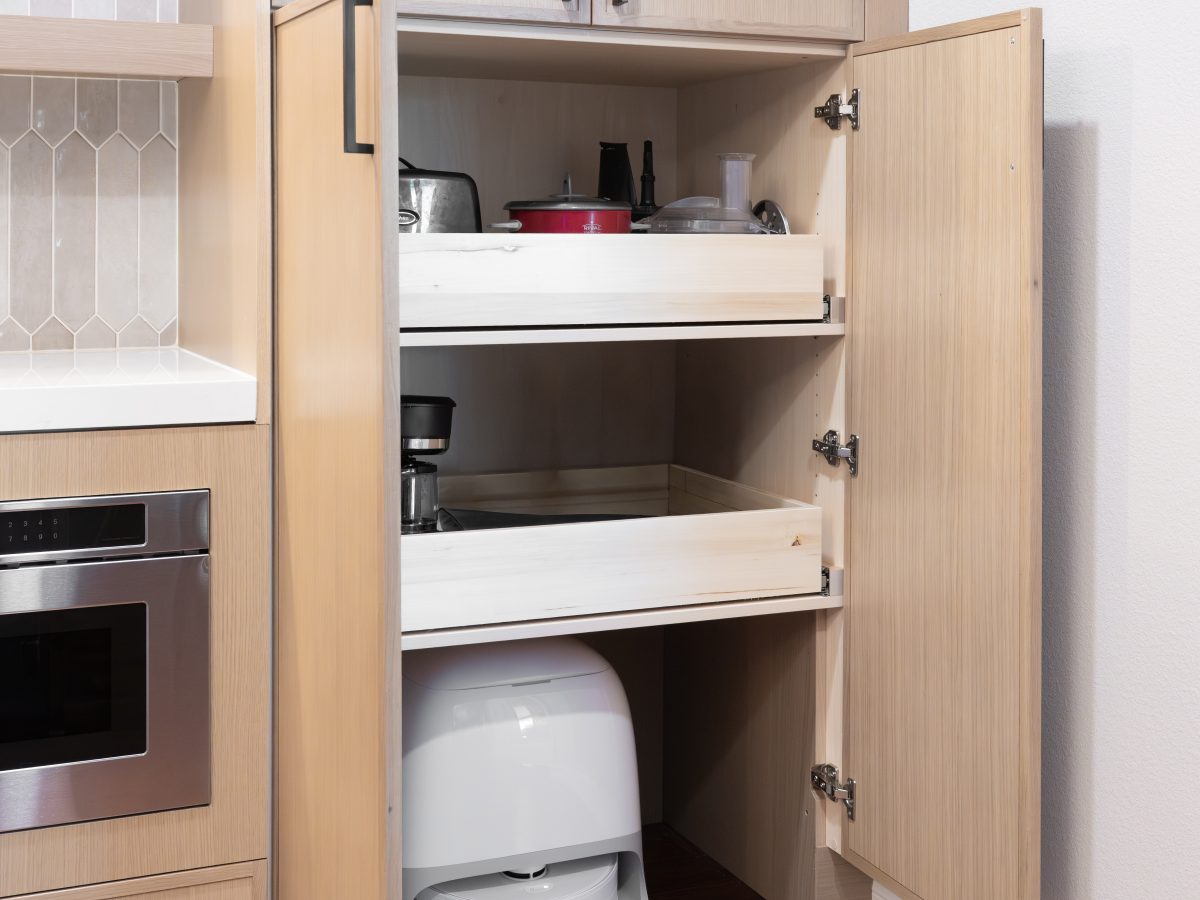 Kitchen appliance cabinet with pull-out shelves and built-in robot vacuum storage, Reveal Interior Design Las Vegas