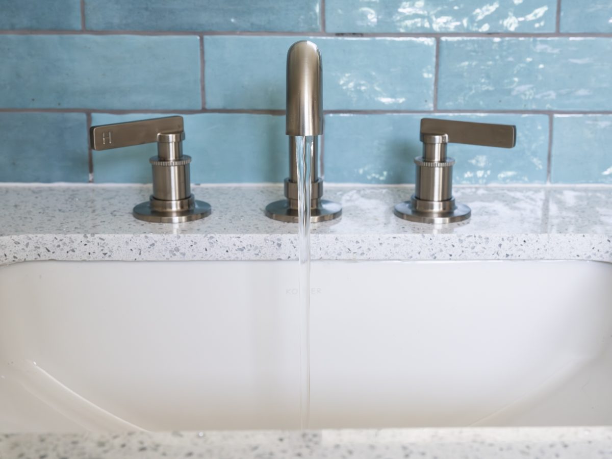 Primary bathroom vanity with white quartz countertop, brushed nickel fixtures, and handmade teal subway tile, Reveal Interior Design Las Vegas