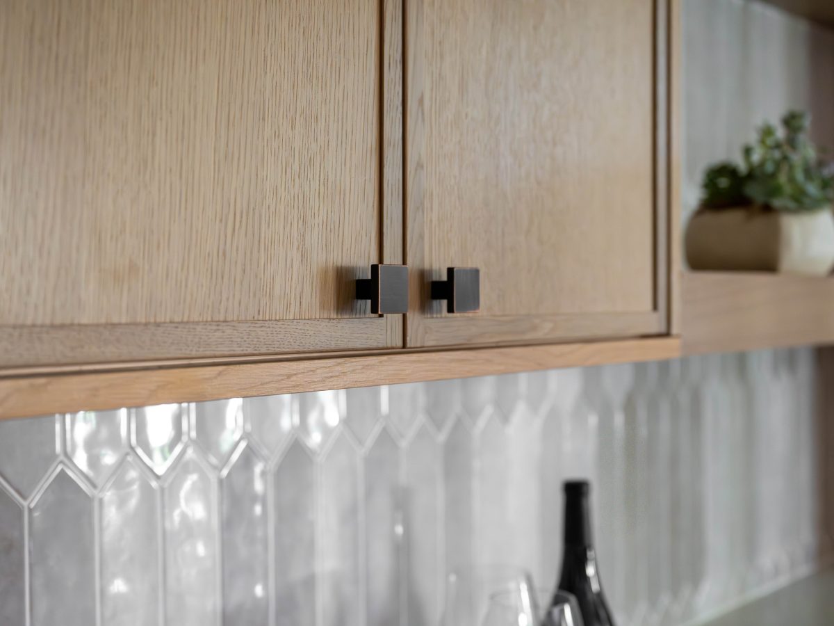 Kitchen upper oak shaker cabinets with dark bronze hardware and handmade-style picket backsplash tile, Reveal Interior Design Las Vegas