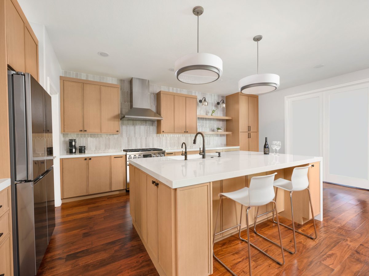 Modern kitchen with warm oak shaker cabinetry, quartz island, and dark bronze fixtures, Reveal Interior Design Las Vegas