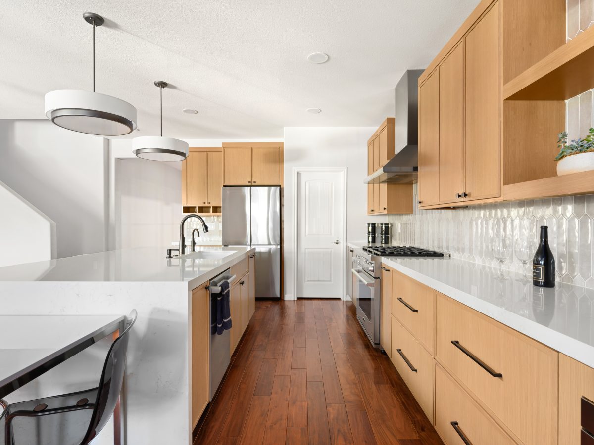 Galley kitchen with warm oak shaker cabinetry, quartz countertops, and picket backsplash tile, Reveal Interior Design Las Vegas