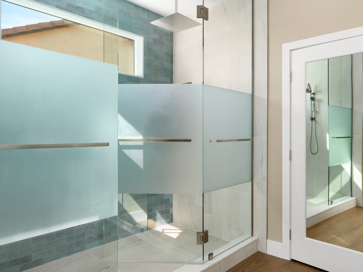 Primary bathroom walk-in shower with custom privacy glass and handmade teal subway tile, Reveal Interior Design Las Vegas