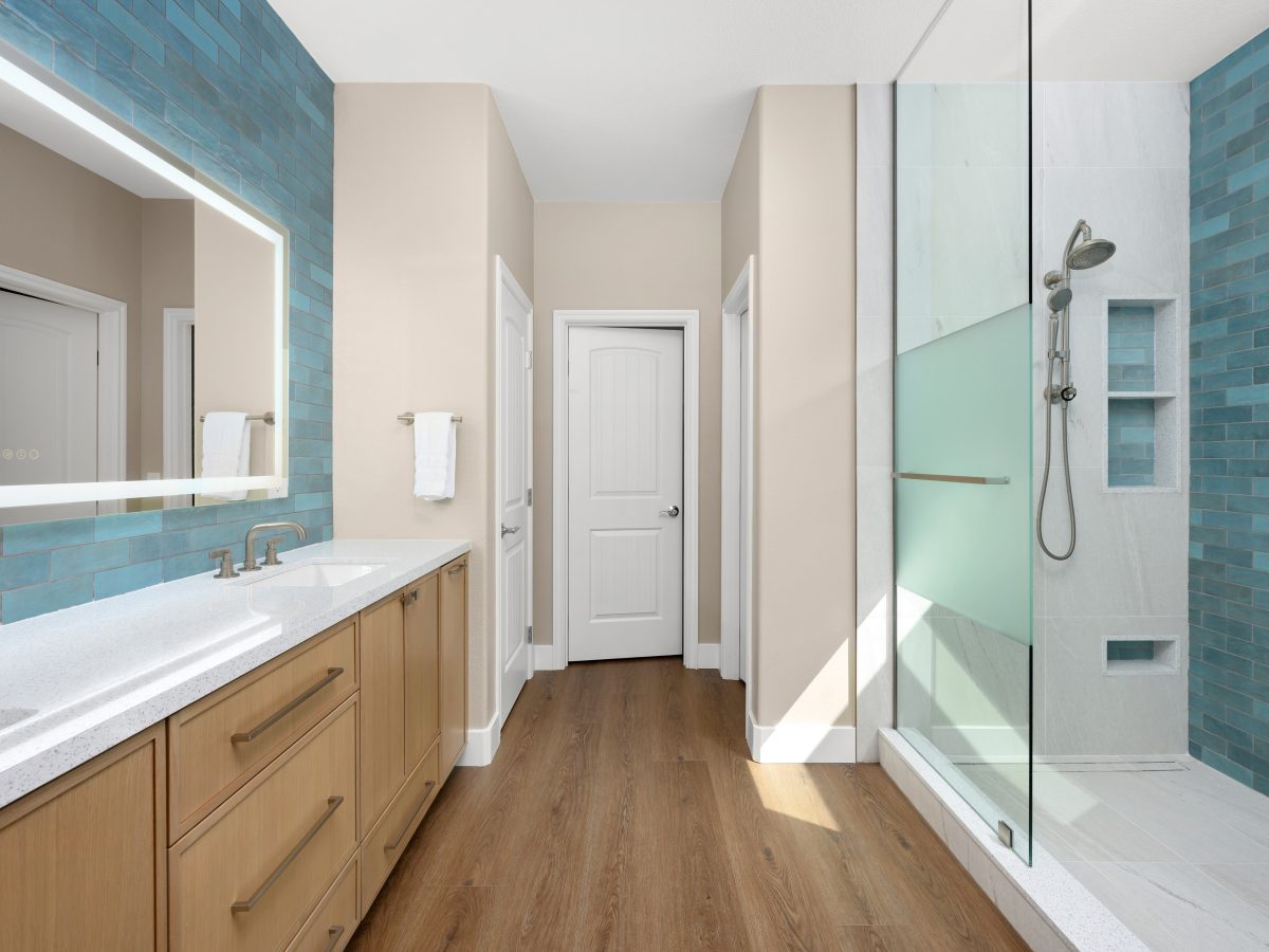 Spa primary bathroom with handmade teal subway tile, two-person walk-in shower, and warm oak vanity, Reveal Interior Design Las Vegas