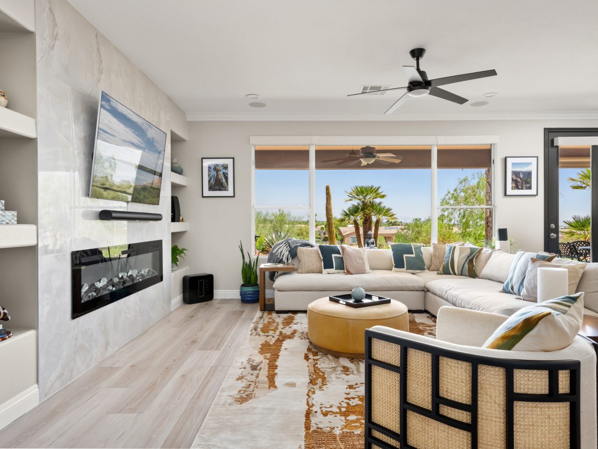 Desert Modern living room with butterscotch leather ottoman and cane-back swivel chair, Reveal Interior Design Las Vegas