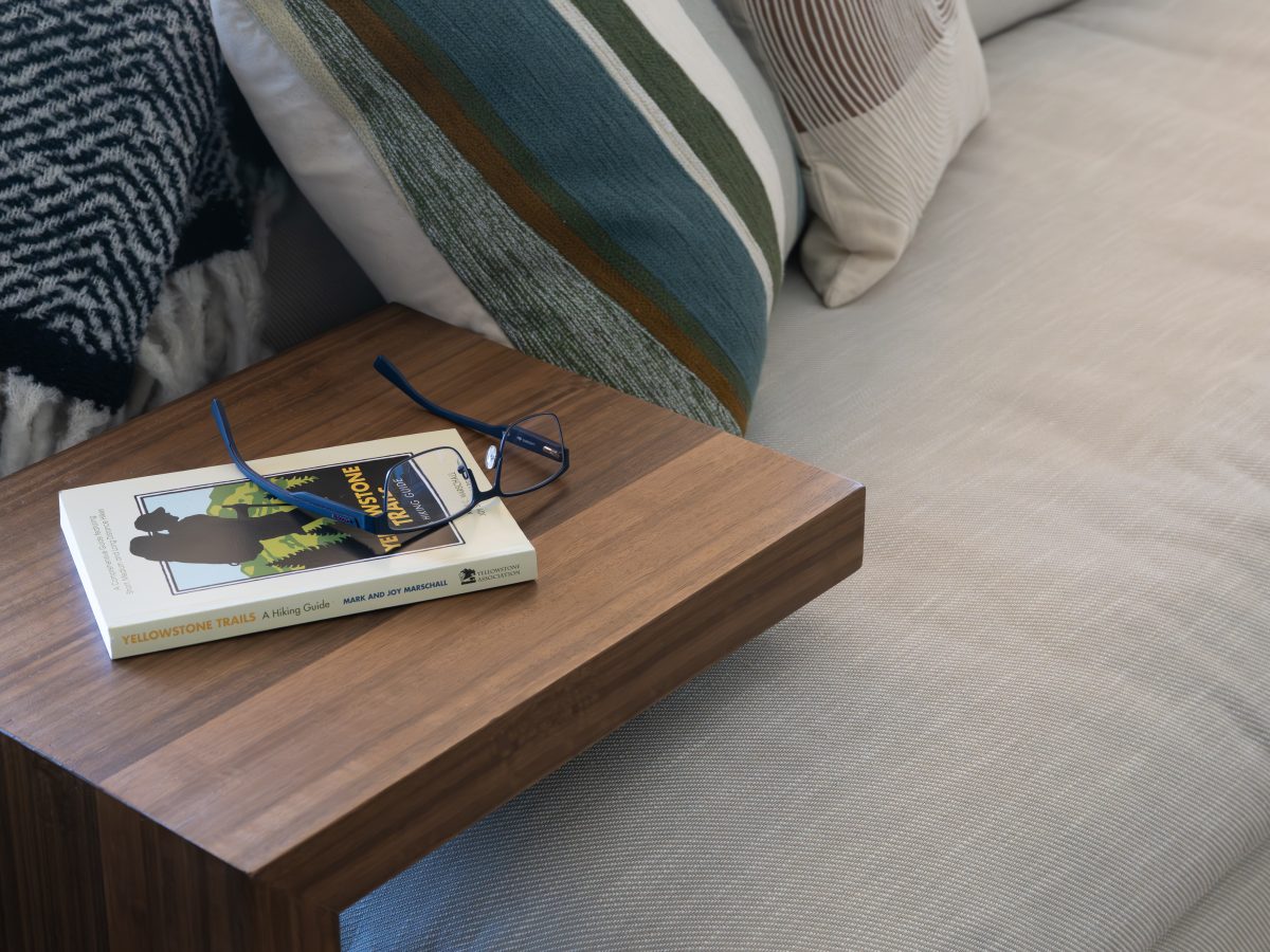 Living room walnut side table with hiking book and reading glasses beside oatmeal sectional sofa, Reveal Interior Design Las Vegas