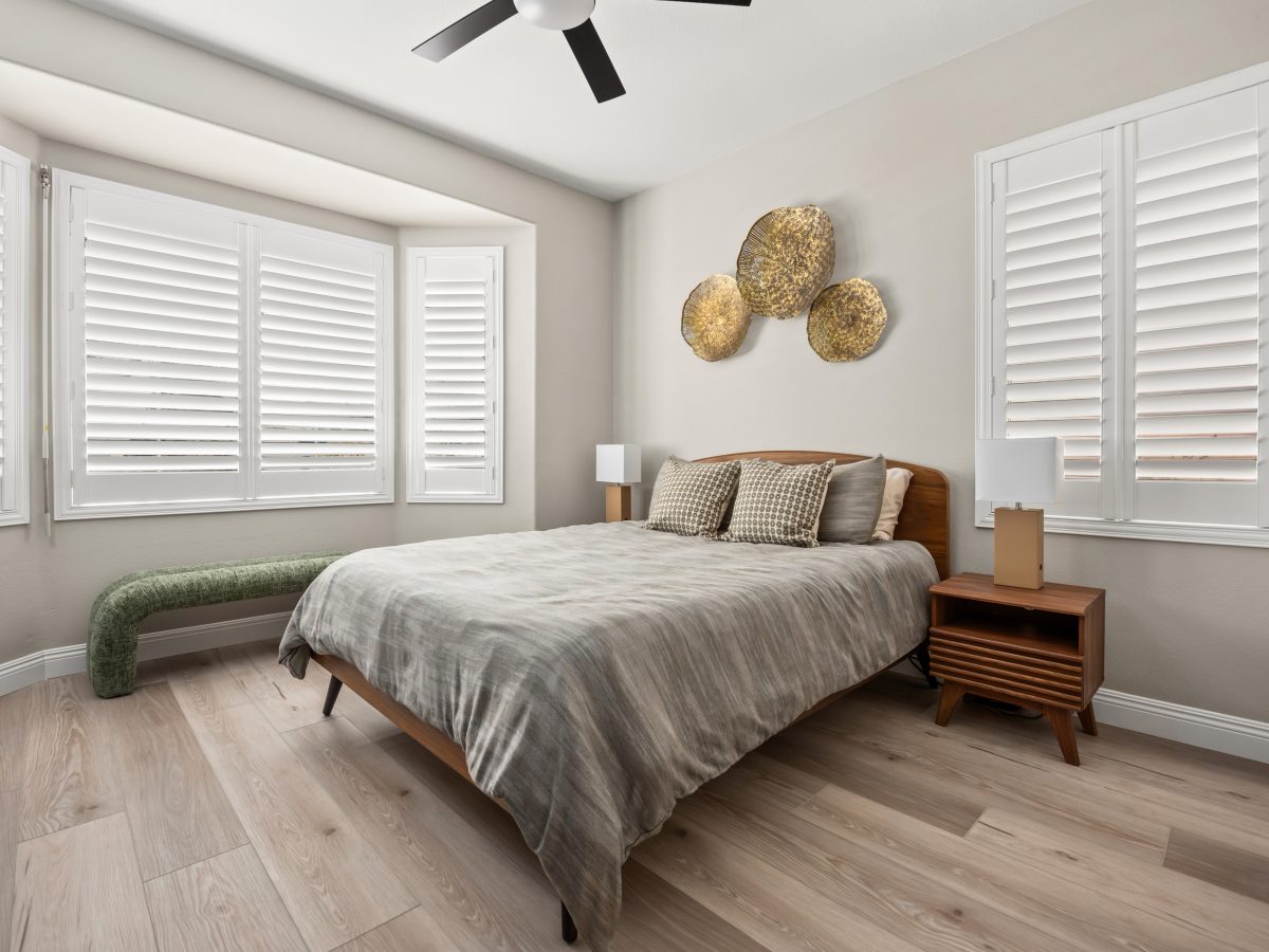 Mid-century modern bedroom with walnut headboard, wood-look flooring, and sculptural metal wall art, Reveal Interior Design Las Vegas