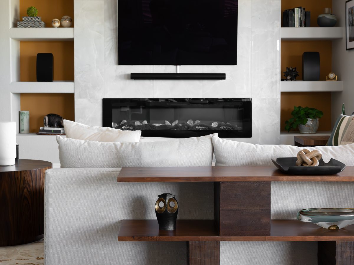 Contemporary living room with light-veined stone media wall, built-in shelving, and linear fireplace, Reveal Interior Design Las Vegas