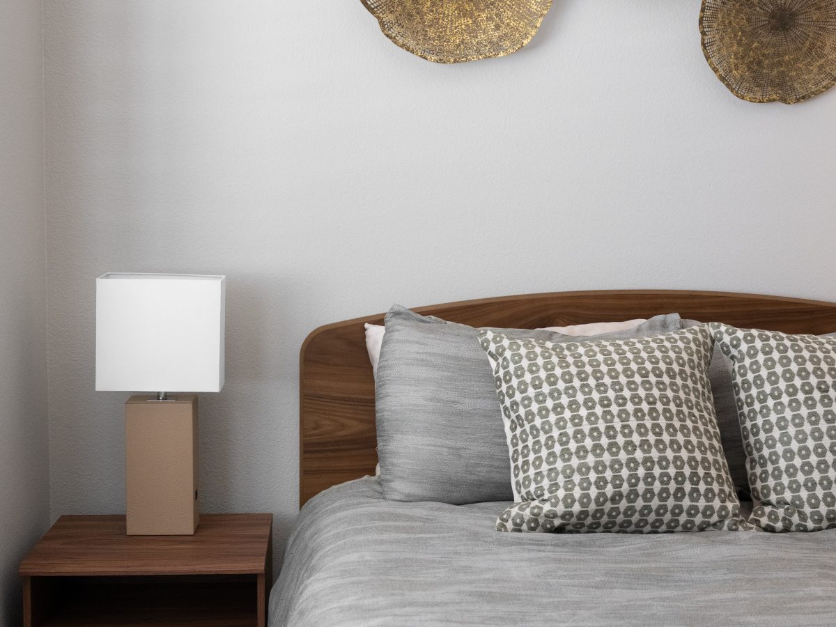 Contemporary bedroom with walnut headboard, dimensional gold metal wall art, and wood-look flooring, Reveal Interior Design Las Vegas