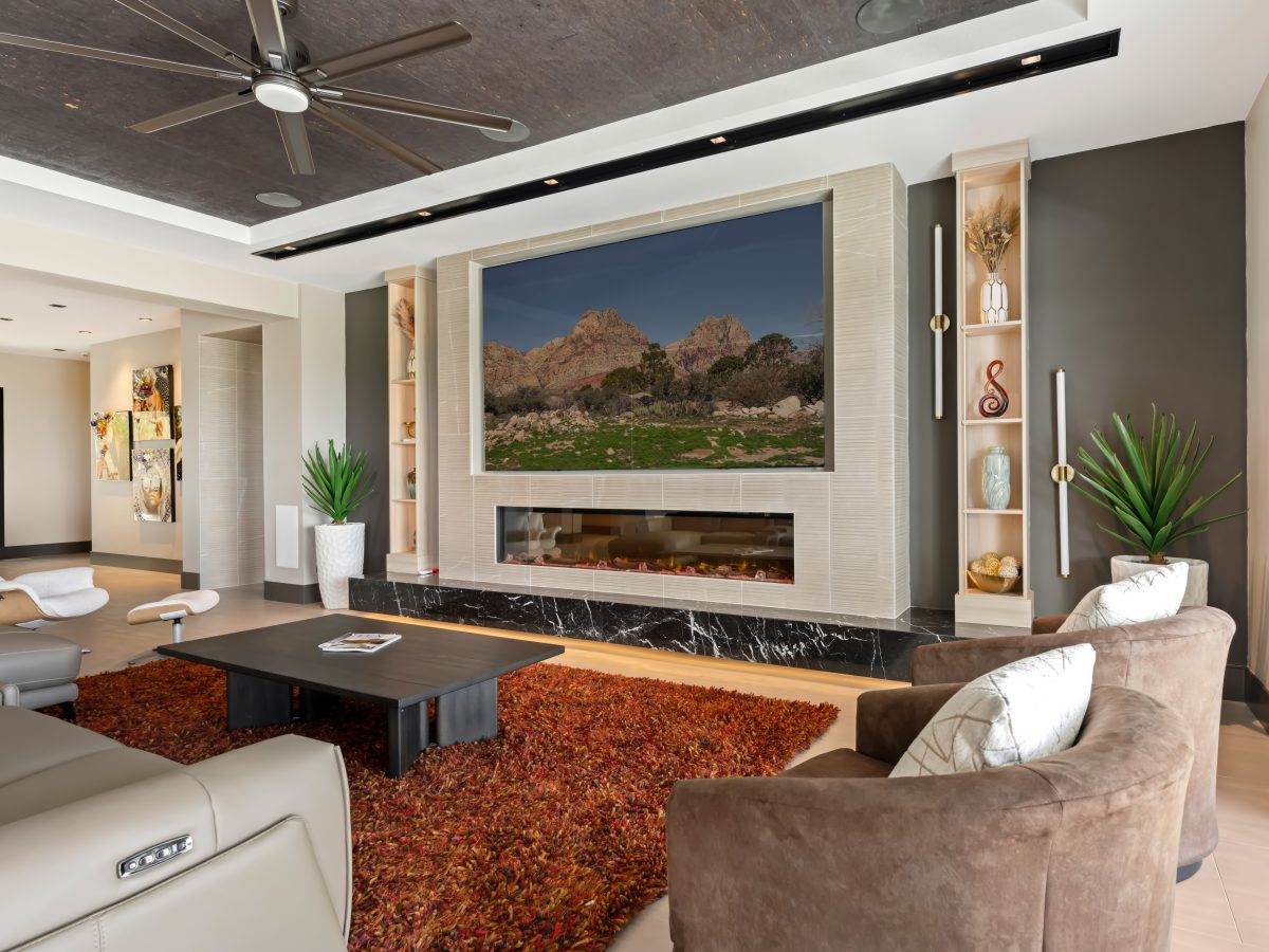 Living room with custom light wood bookcase cabinetry, linear fireplace, and four-panel TV wall, Reveal Interior Design Las Vegas