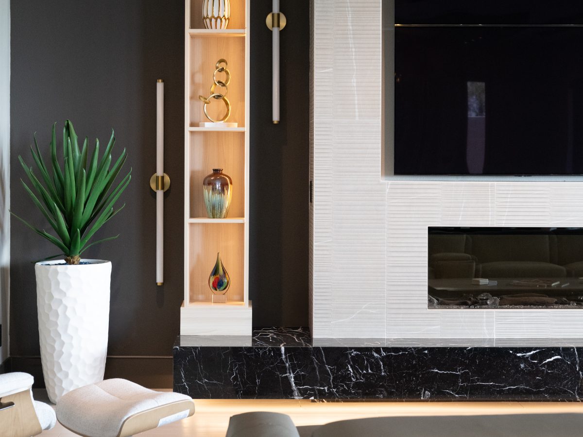 Living room with custom light wood bookcase niche, floating black marble hearth, and large linear fireplace, Reveal Interior Design Las Vegas