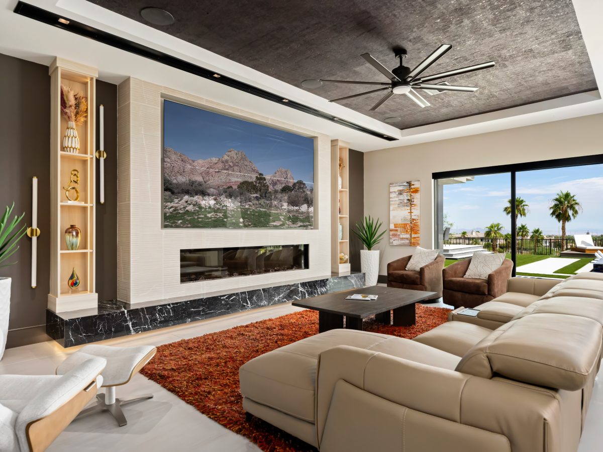 Living room with four-panel TV niche, custom light wood cabinetry, and floating black marble hearth, Reveal Interior Design Las Vegas