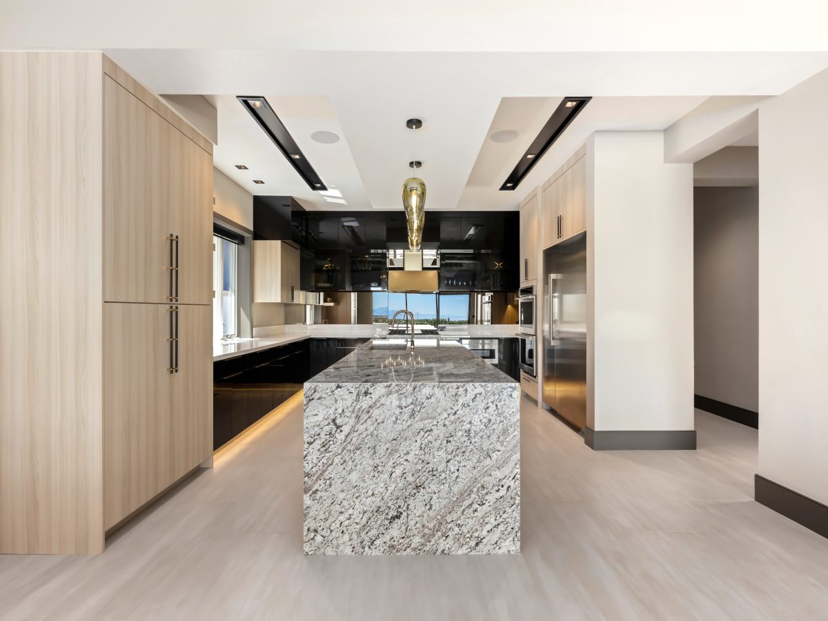 Luxury kitchen with granite waterfall island, dark charcoal and white oak cabinetry, Reveal Interior Design Las Vegas