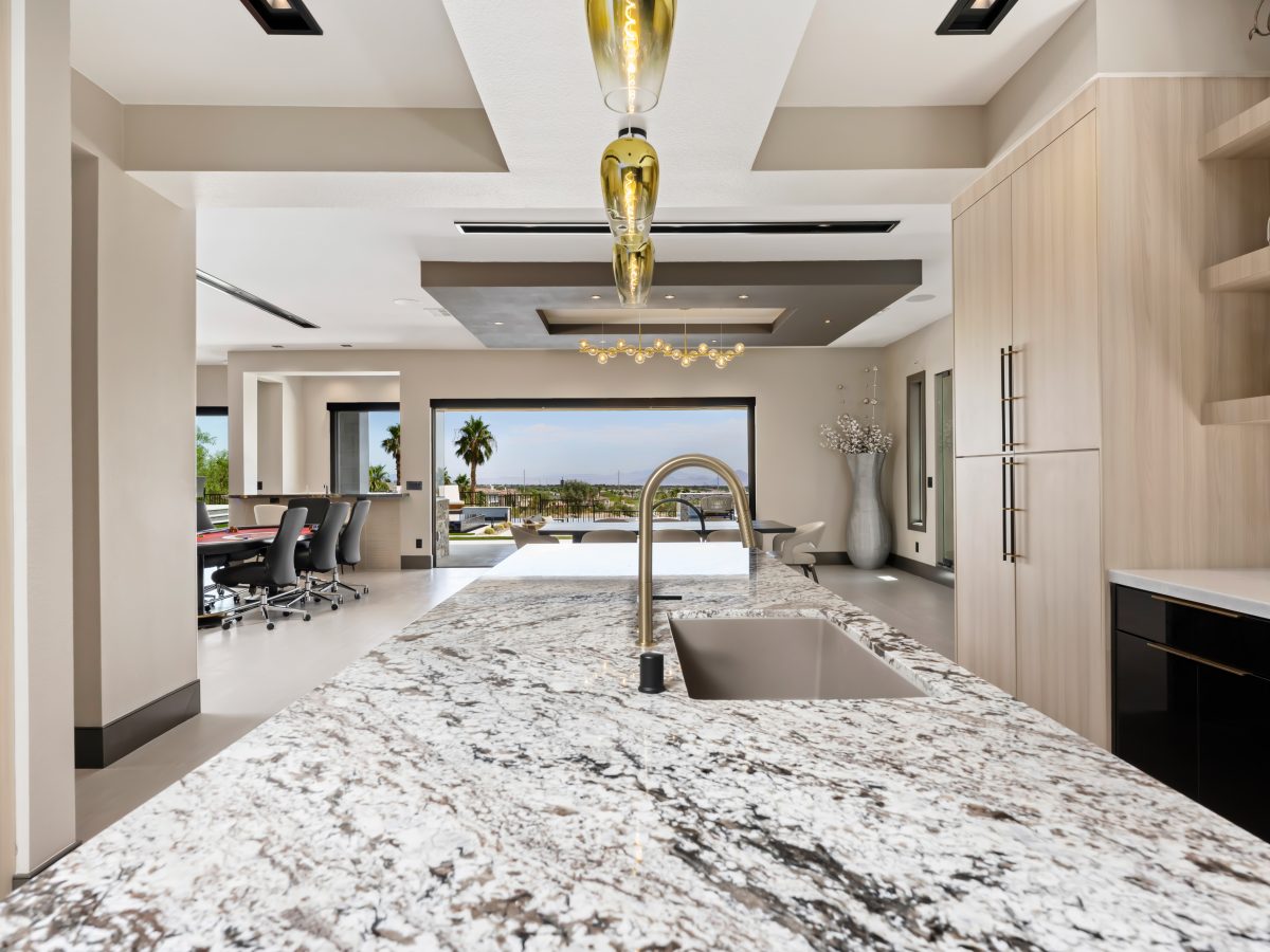 Granite island kitchen with white oak cabinetry, gold fixtures, and mirrored backsplash, Reveal Interior Design Las Vegas