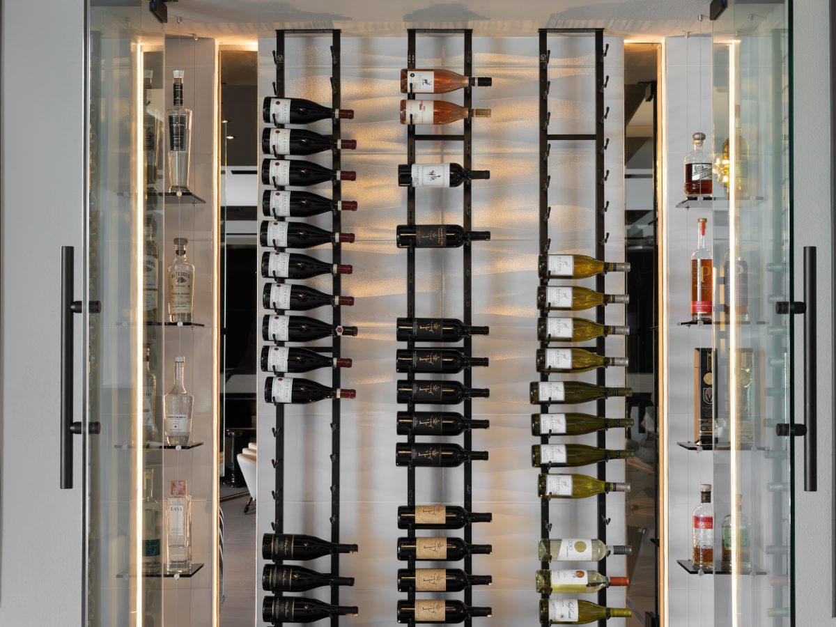 Custom wine niche with modern metal shelving, mirrored panels, and hidden LED lighting, Reveal Interior Design Las Vegas
