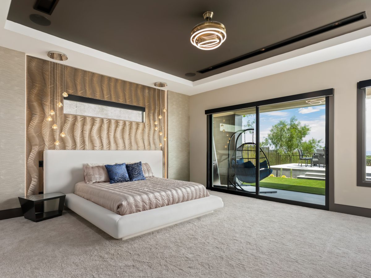 Primary bedroom with Urbane Bronze tray ceiling, gold textured wall panels, and platform bed, Reveal Interior Design Las Vegas