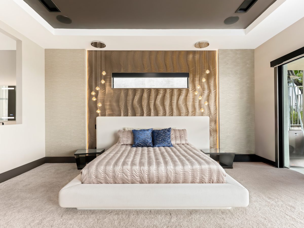Primary bedroom with gold bronze textured panel accent wall, platform bed, and multi-drop pendant lighting, Reveal Interior Design Las Vegas