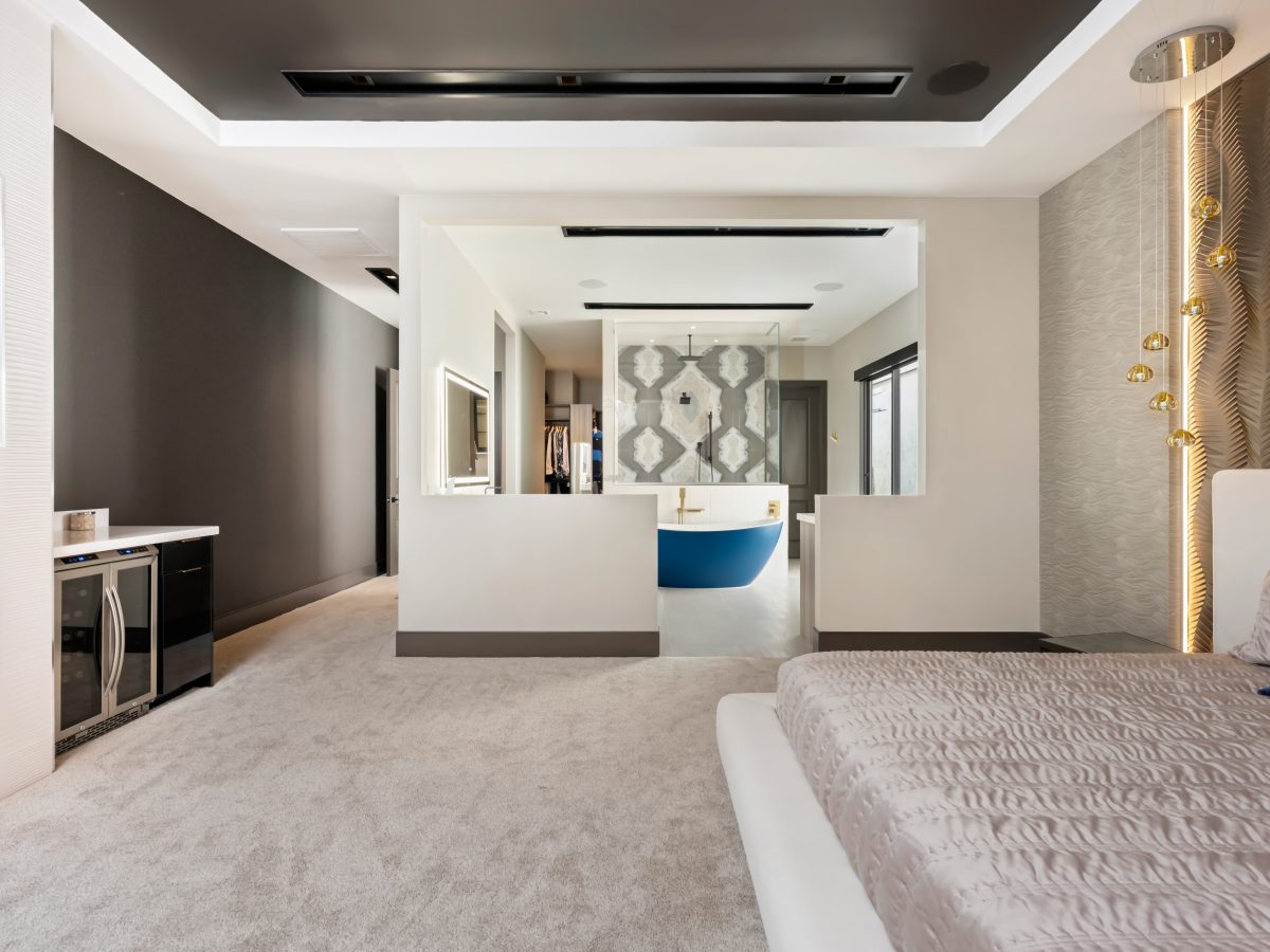 Primary bedroom with Urbane Bronze ceiling, open-plan bathroom, and gold textured wall panels, Reveal Interior Design Las Vegas
