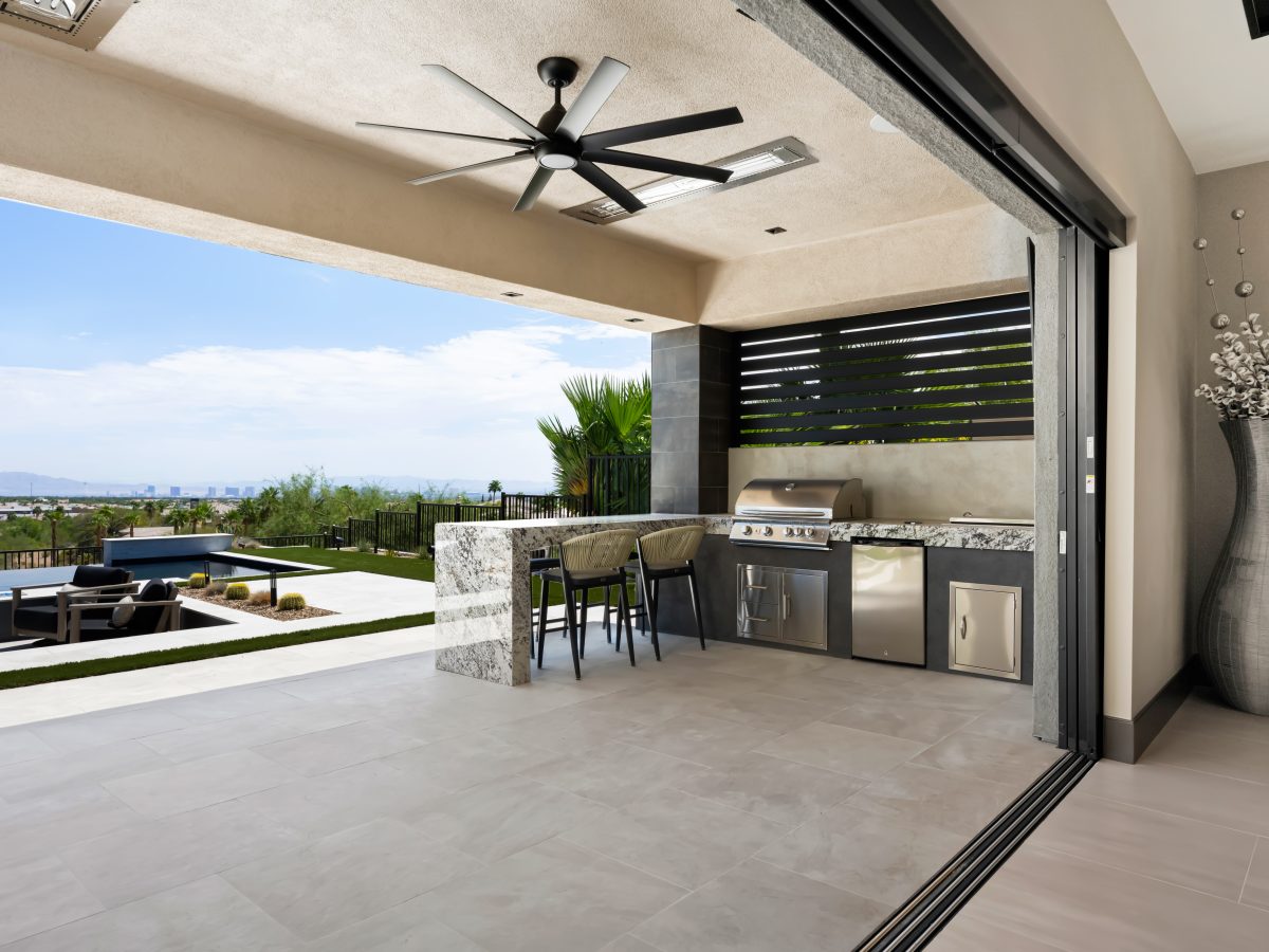 Covered outdoor kitchen with granite island, built-in BBQ, and large-format porcelain tile, Reveal Interior Design Las Vegas