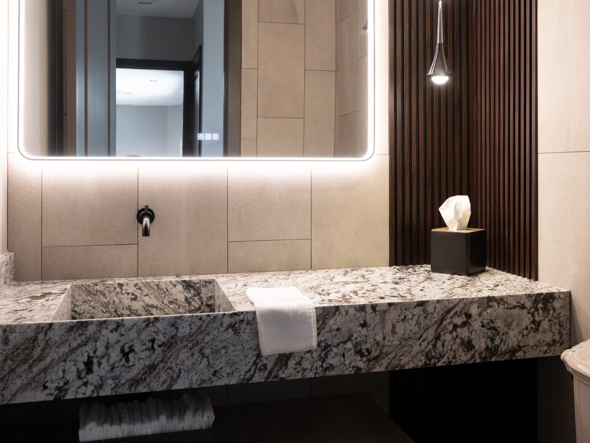 Powder bath with granite floating vanity, integrated sink, LED mirror, and multi-drop pendants, Reveal Interior Design Las Vegas
