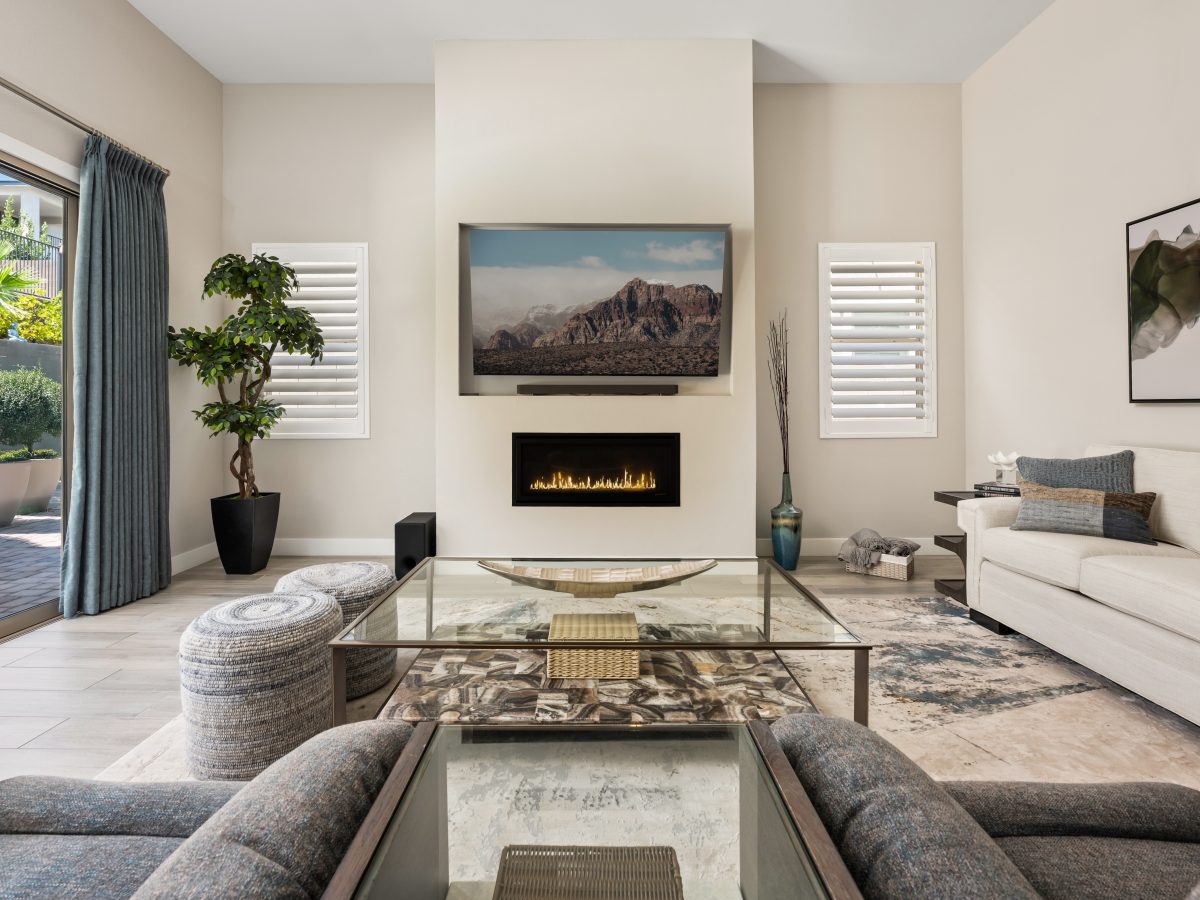 Contemporary living room with linear fireplace, glass and natural stone coffee table, and curated tropical accents, Reveal Interior Design Las Vegas