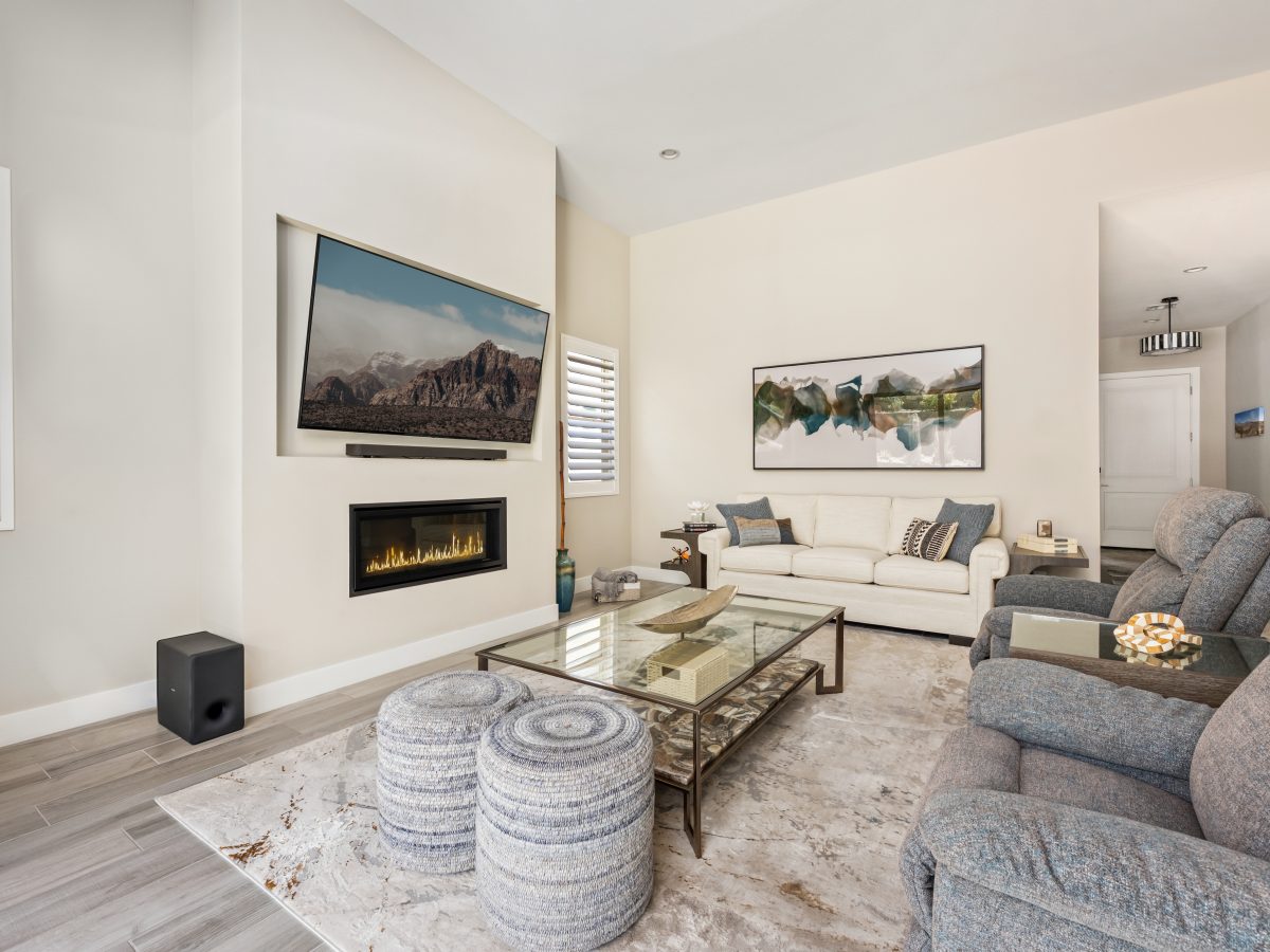 Contemporary living room with glass and natural stone coffee table, blue-gray recliners, and custom off-white sofa, Reveal Interior Design Las Vegas