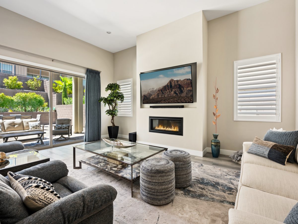 Contemporary living room with glass and natural stone coffee table, gas fireplace, and custom off-white sofa, Reveal Interior Design Las Vegas