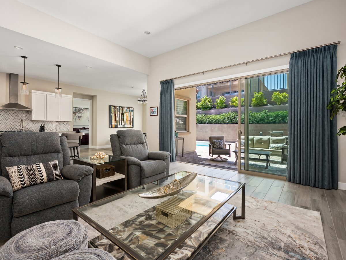Contemporary living room with recliner seating, glass and natural stone coffee table, and patio views, Reveal Interior Design Las Vegas