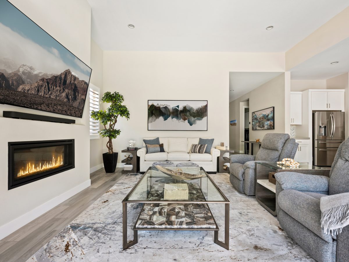 Contemporary living room with glass and natural stone coffee table, blue-gray recliners, and linear fireplace, Reveal Interior Design Las Vegas