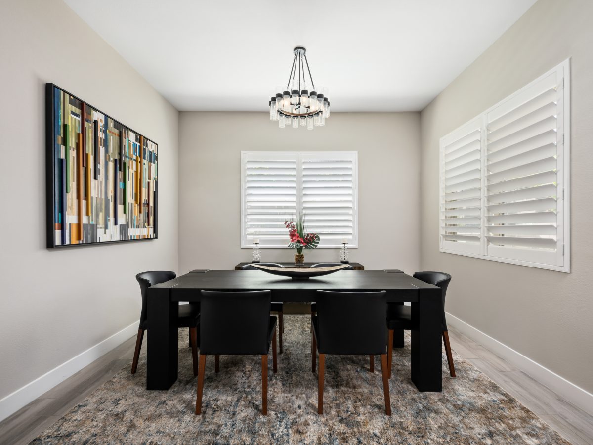 Modern dining room with chunky black dining table, barrel chairs, and crystal ring chandelier, Reveal Interior Design Las Vegas