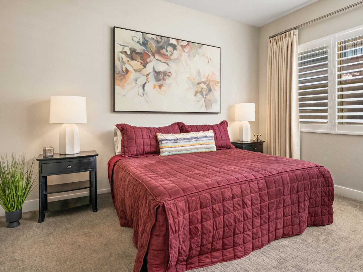 Primary bedroom with cranberry quilted comforter and large contemporary floral art, Reveal Interior Design Las Vegas