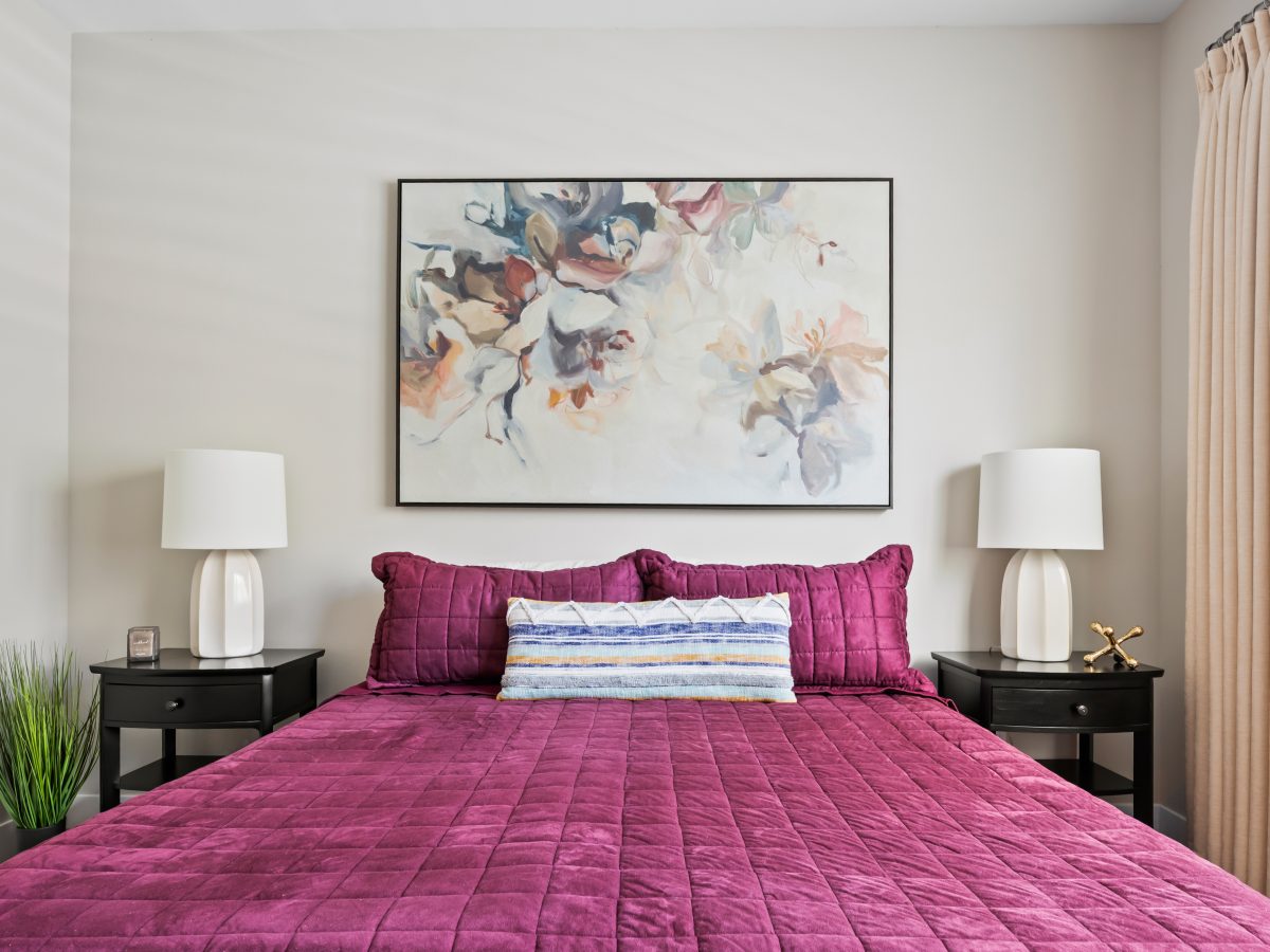 Contemporary bedroom with magenta velvet quilted bedding and abstract floral artwork, Reveal Interior Design Las Vegas