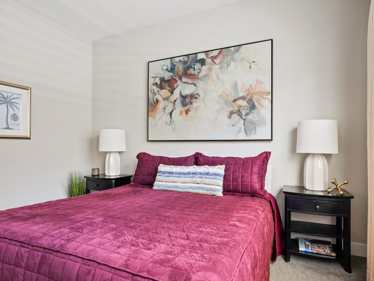 Primary bedroom with cranberry velvet comforter and large contemporary floral artwork, Reveal Interior Design Las Vegas
