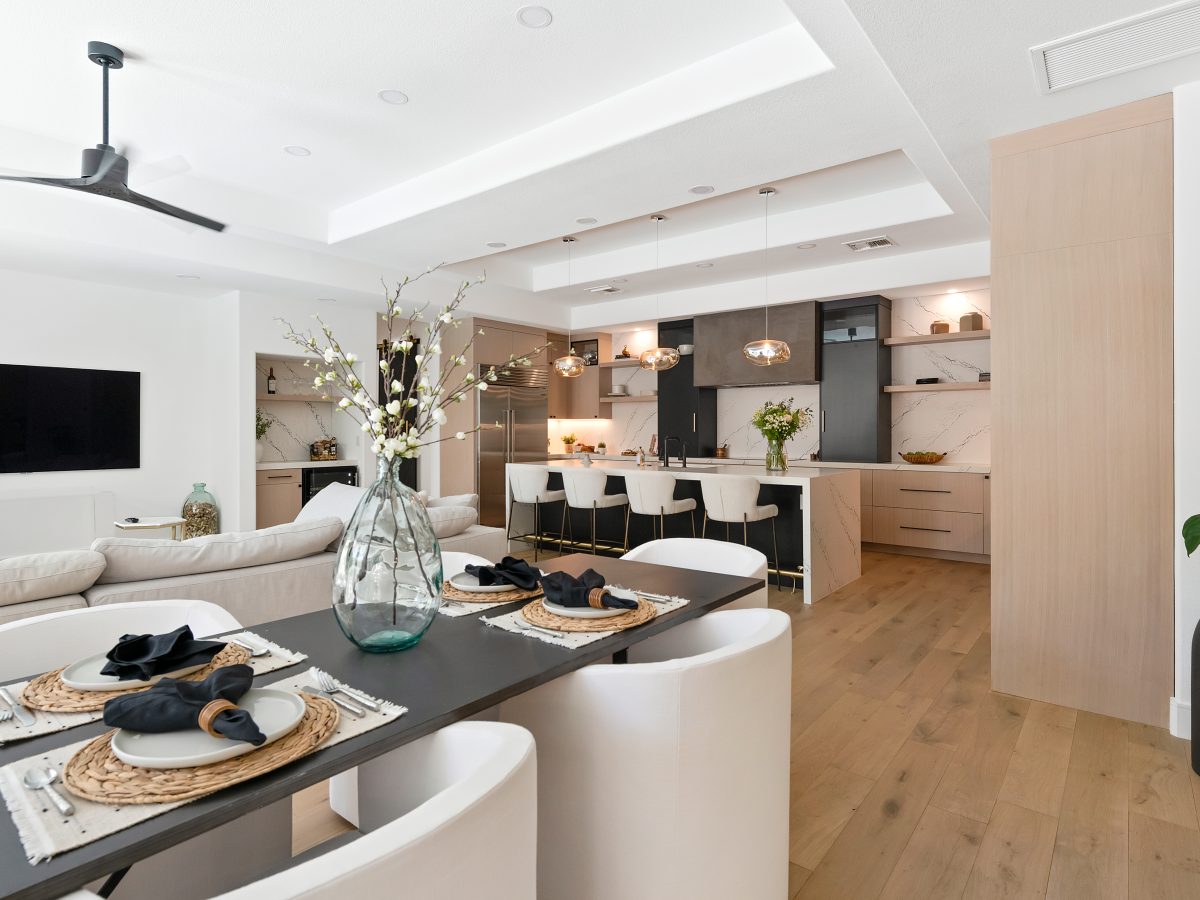 Open-concept kitchen with white-washed oak cabinetry, black quartz countertops, and matte black range hood, Reveal Interior Design Las Vegas