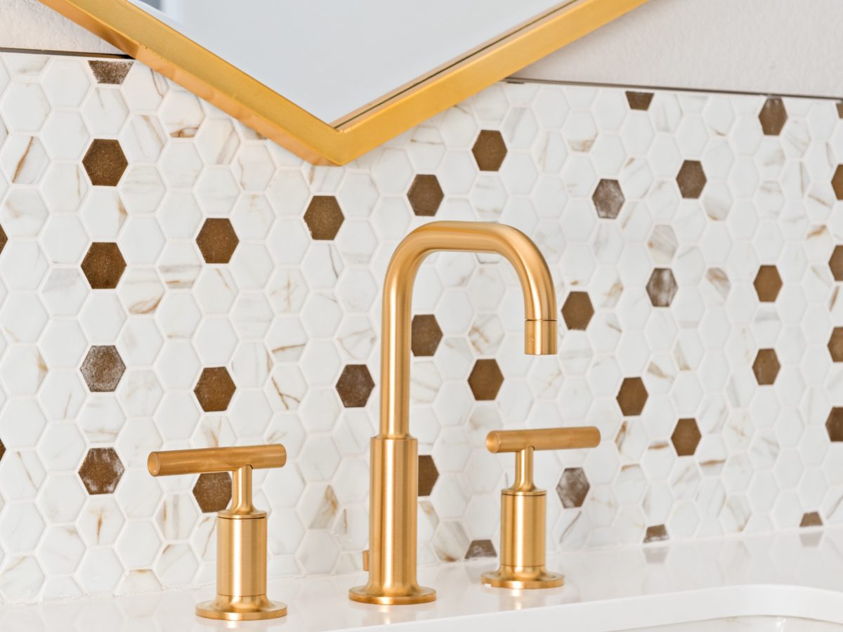 Primary bathroom vanity with gold widespread faucet and calacatta-look glass mosaic tile backsplash, Reveal Interior Design Las Vegas