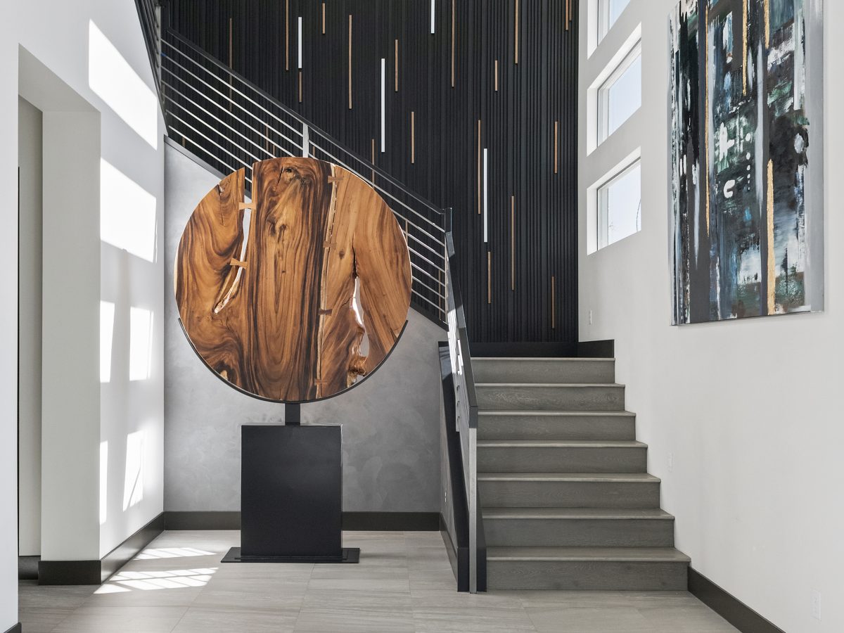 Grand entryway with live-edge wood sculpture, extruded black metal accent wall with LED lighting, Reveal Interior Design Las Vegas