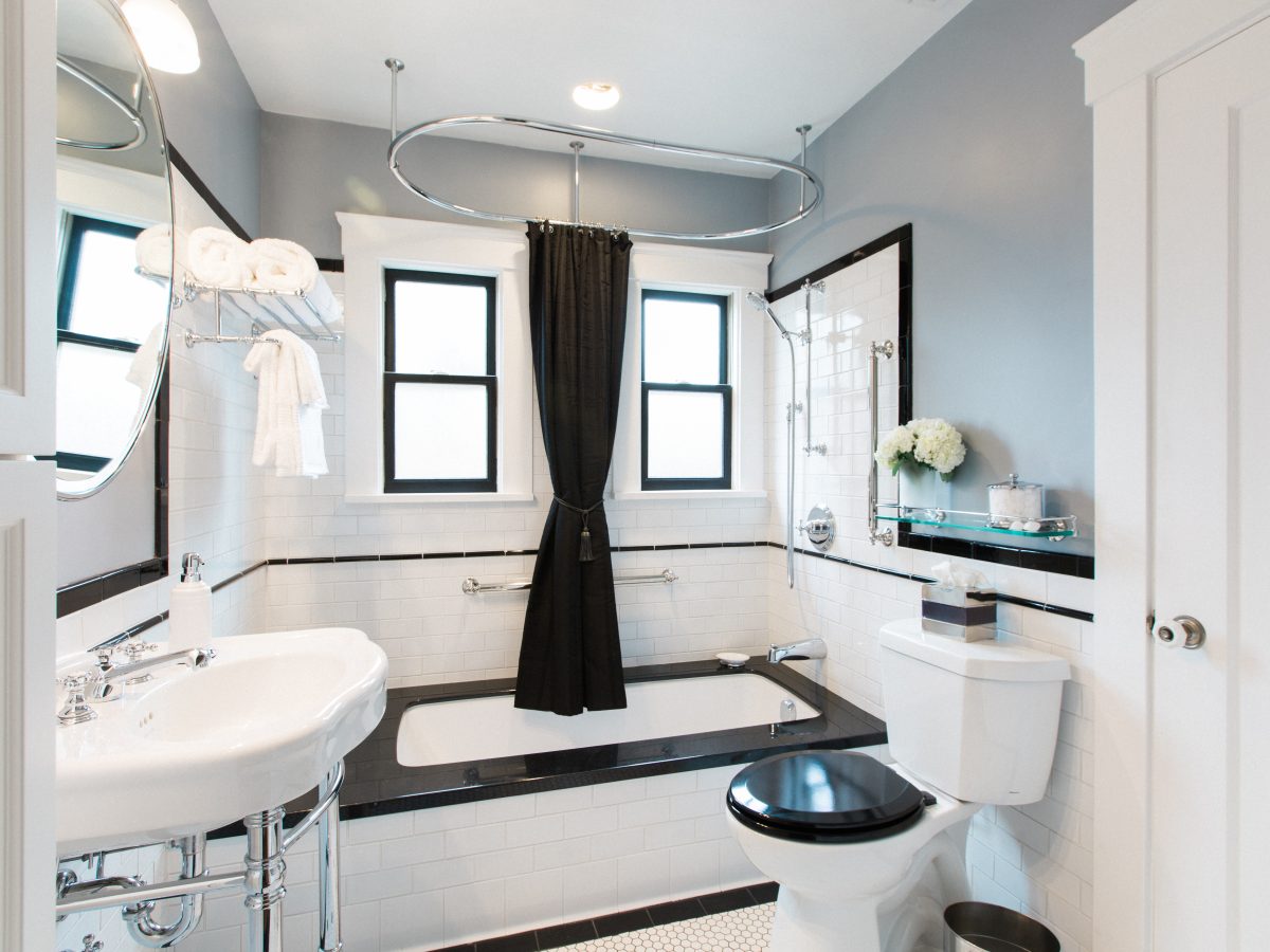 1920s historic bathroom with black granite drop-in tub, white subway tile, and hex mosaic floor, Reveal Interior Design Las Vegas