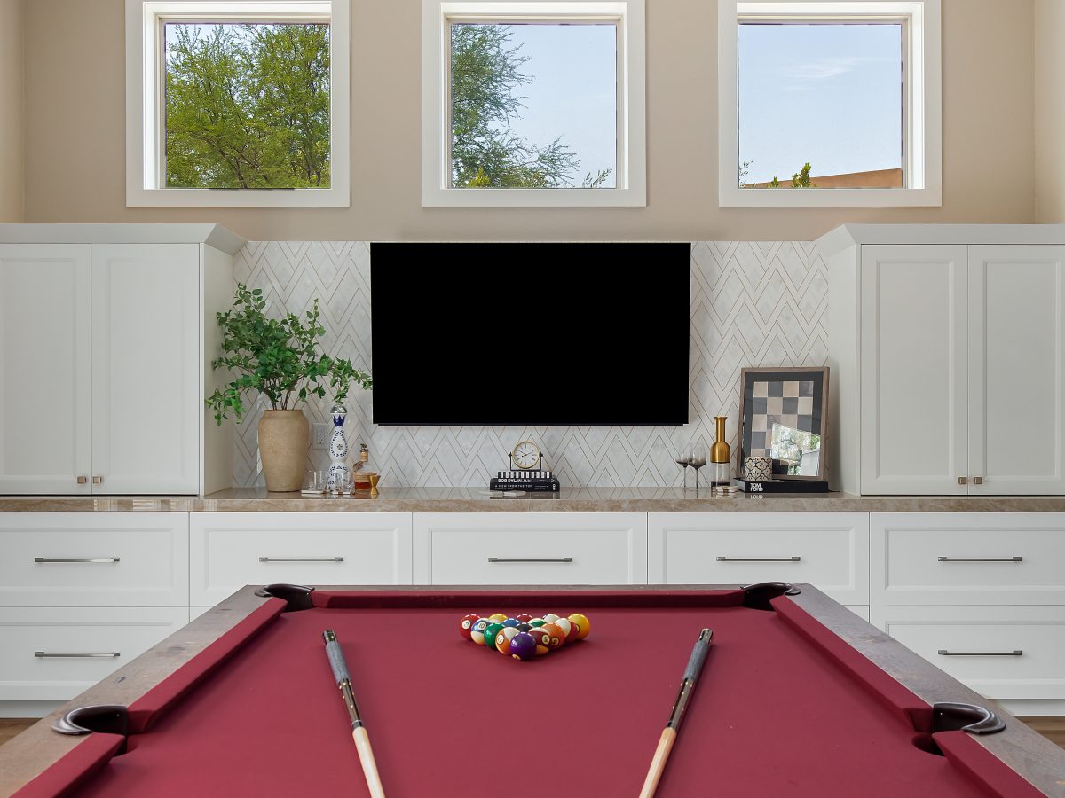 Game room with red felt pool table, white shaker cabinetry, and herringbone tile feature wall, Reveal Interior Design Las Vegas