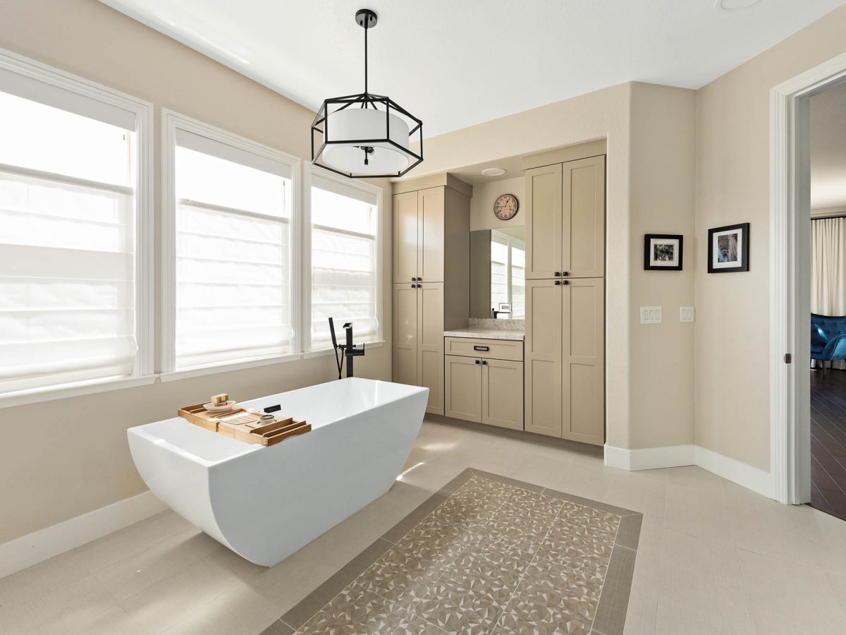Primary bathroom with freestanding tub, warm beige cabinetry, and quartz countertops, Reveal Interior Design Las Vegas
