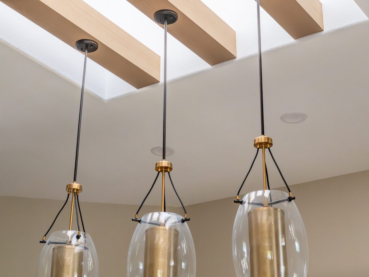 Kitchen pendant lights with brass and glass globes beneath a beamed skylight, Reveal Interior Design Las Vegas