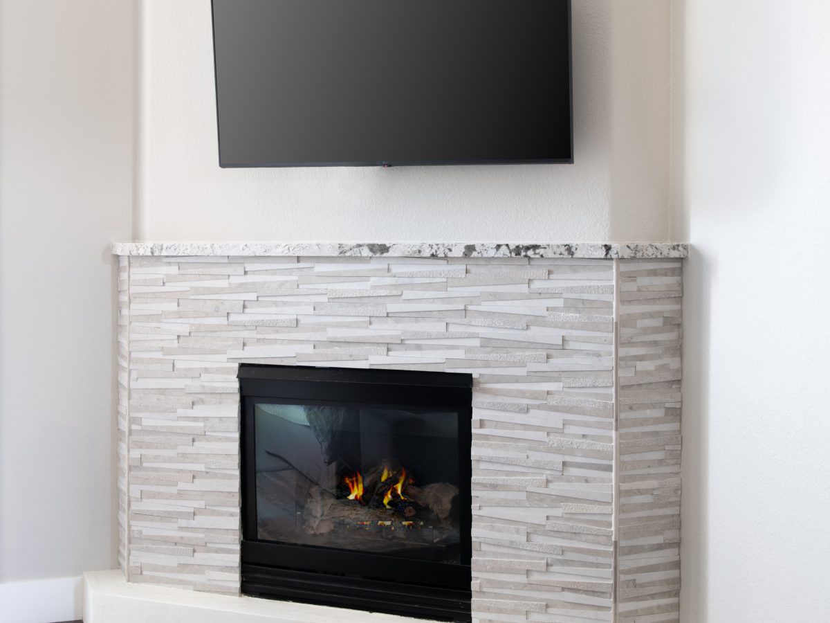 Corner fireplace with dimensional stone surround and granite mantel, Reveal Interior Design Las Vegas