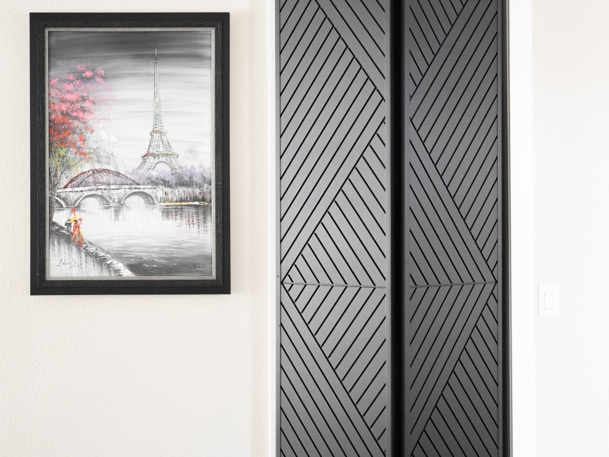 Custom bi-fold barn door with geometric pattern and Paris-themed wall art, Reveal Interior Design Las Vegas