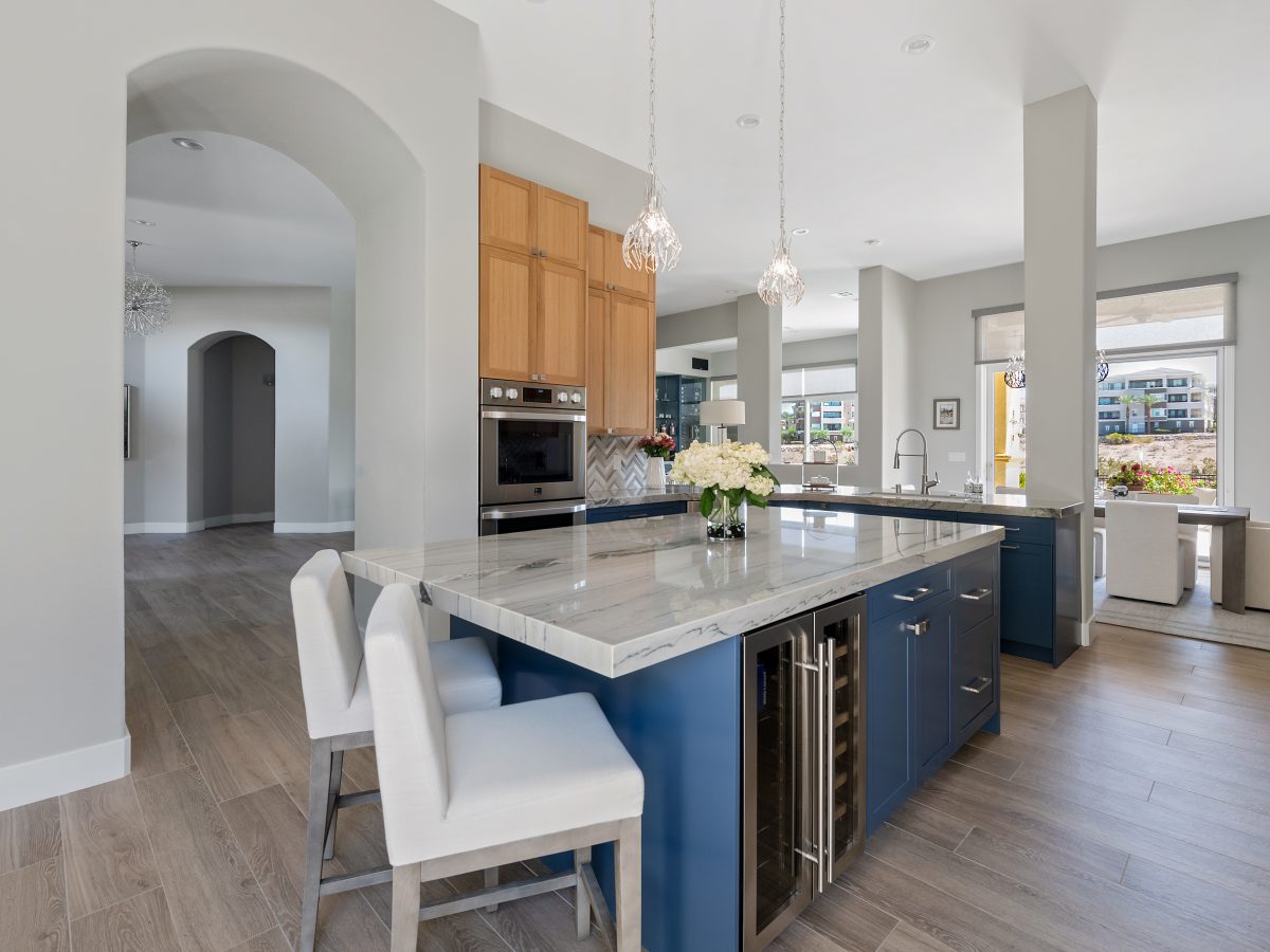 Kitchen with dark navy island, warm oak upper cabinets, and quartzite countertops, Reveal Interior Design Las Vegas