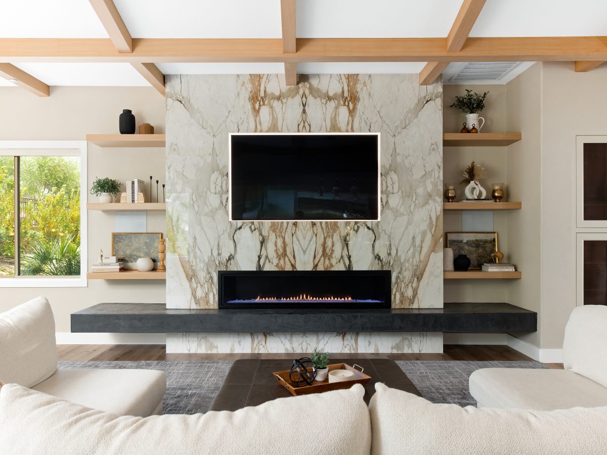 Living room with bookmatched porcelain slab fireplace surround, backlit TV, and oak beam ceiling, Reveal Interior Design Las Vegas