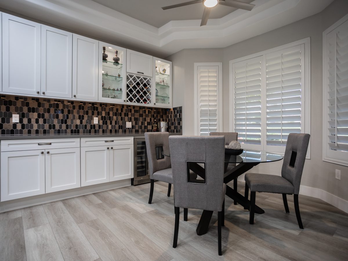 Kitchen breakfast nook with white shaker cabinetry, hex mosaic backsplash, and wine storage, Reveal Interior Design Las Vegas