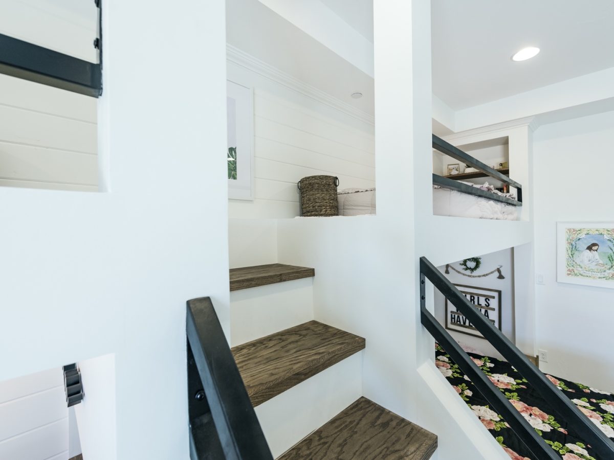 Custom triple bunk bedroom with white millwork, black metal framing, and warm wood stair treads, Reveal Interior Design Las Vegas