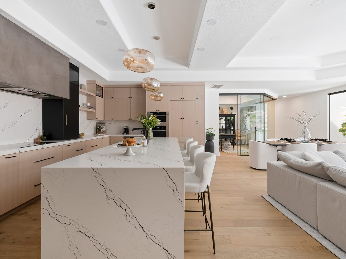 Open-concept kitchen with black-veined white quartz island, whitewashed oak cabinetry, and matte black accents, Reveal Interior Design Las Vegas