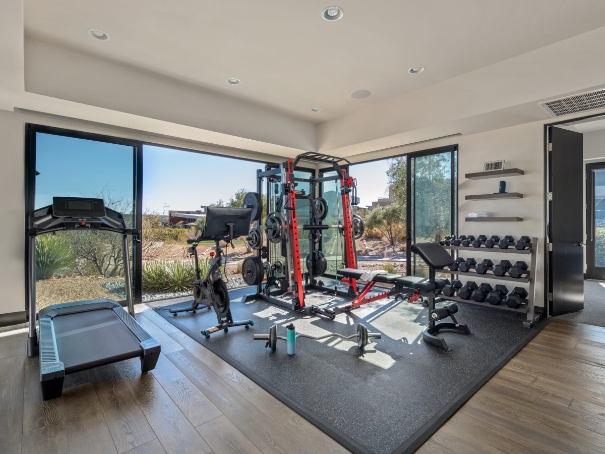 Desert Modern home gym with floor-to-ceiling glass, power rack, and dumbbell wall, Reveal Interior Design Las Vegas
