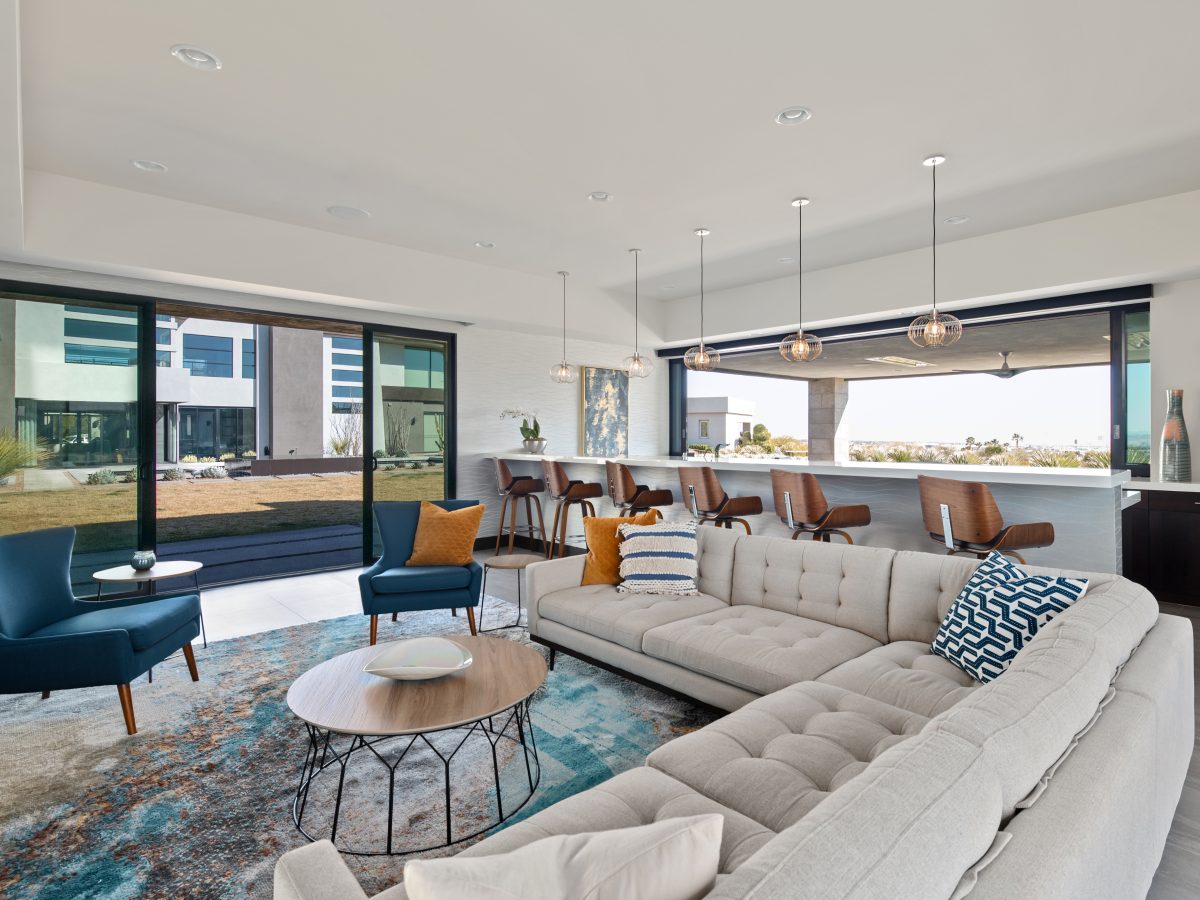 Casita living room and bar with tufted sectional, teal accent chairs, and quartz bar counter, Reveal Interior Design Las Vegas
